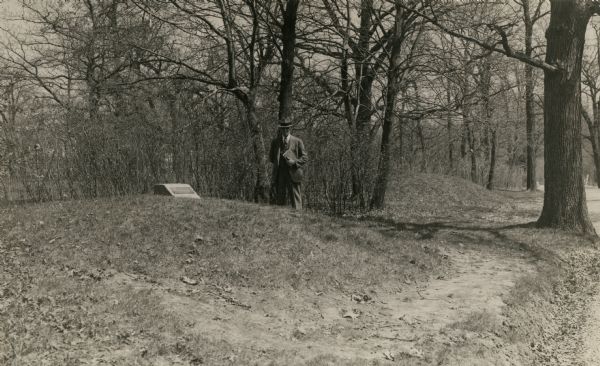 Charles E. Brown poses near a historic tablet marking one of a row of conical burial mounds on the Park and Pleasure drive on the north shore of Lake Wingra. These mounds are now incorporated within the Edgewood College campus.
