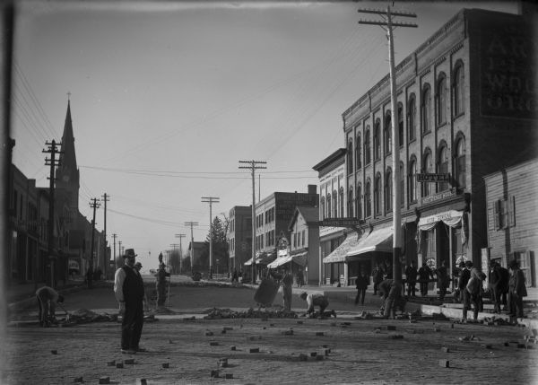 Paving Watertown's main street with bricks, with almost as many men who are watching as construction workers.