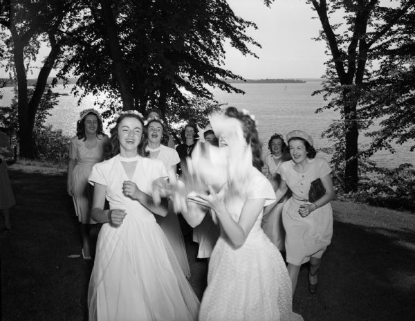 Women assembled for the bride's bouquet toss at the Helen Louise Hadley-Dr. John Farrell Whitman wedding reception at the Alpha Xi Delta sorority house, 12 Langdon Street. Picnic Point and Lake Mendota are visible in the background.