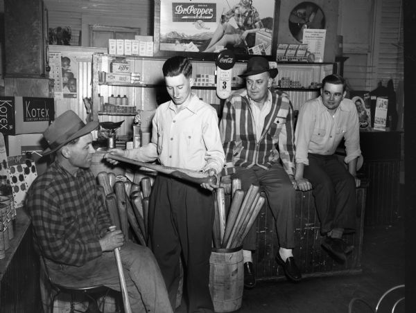 Store interior with two men and two boys looking at baseball bats.