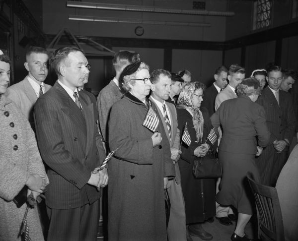 Men and women holding United States flags after a ceremony in the federal courtroom making them naturalized citizens.