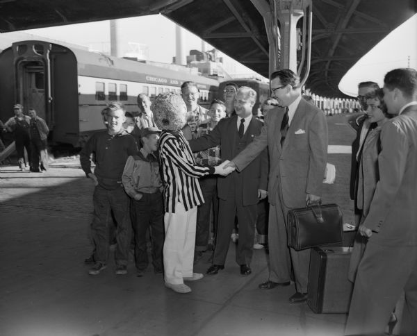 Walt Kelly arriving in Madison at the Chicago & North Western depot, is met by a person dressed as Pogo, one of his cartoon characters.
