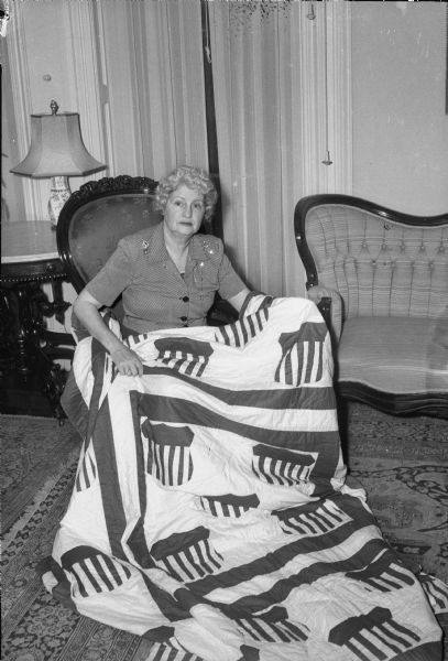 Madge Goodland, wife of Governor Walter Goodland, displaying a quilt with a patriotic design.
