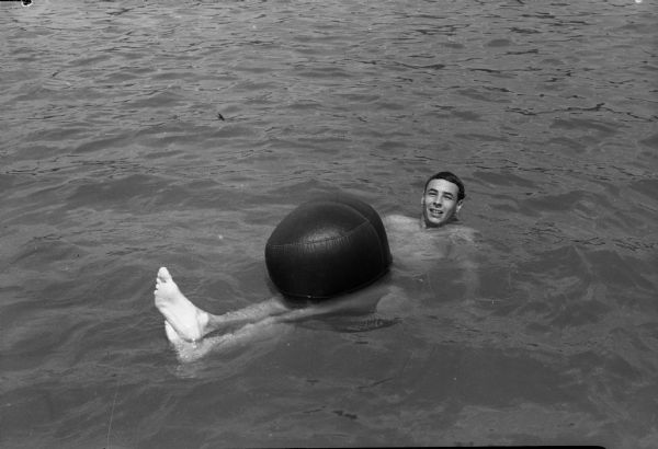 Truax cadet, Pvt. Earl Morwitz, floating with beach ball at Warner Beach.