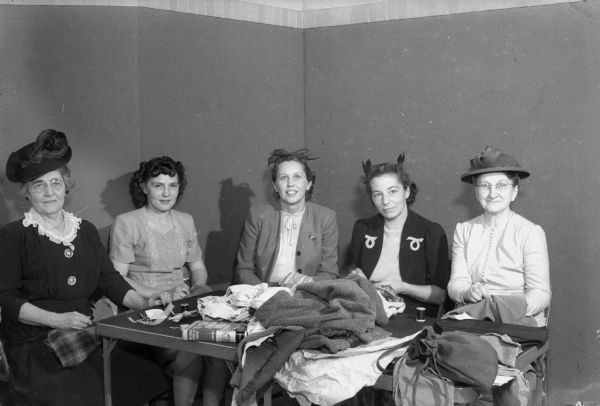 Participating in the Madison Woman's Club annual benefit party by sewing for the Russian War Relief are members of the Shorewood Hills League, left to right: Mrs. M.C. Palmer, 1022 Shorewood Boulevard.; Mrs. Harvey Hubanks, 1101 Amherst Drive; Mrs. Frederic E. (Mary) Mohs, 1240 University Bay Drive; Mrs. R.E. (Dora) Mitchell, 3201 Tally Ho Lane; and Mrs. William D. (Jessie) Tenney, 3610 Sunset Drive.