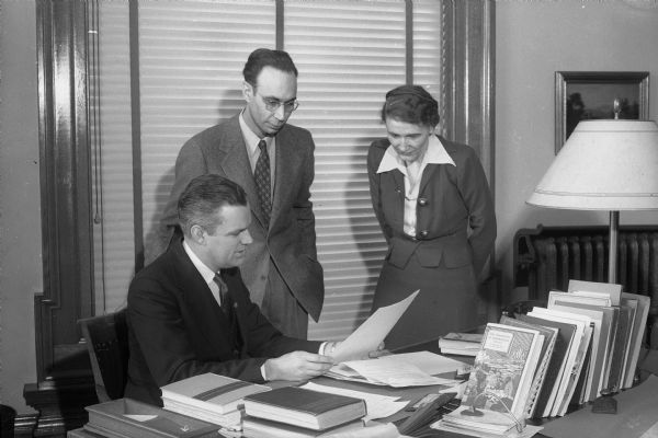 Two men and a woman, members of the Wisconsin Historical Society museum staff, at a desk.