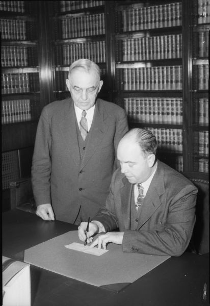 Chief Justice Marvin B. Rosenberry, honorary president of the Wisconsin War Fund, and Frank Ross, president, signing a check for $500,000.00.
