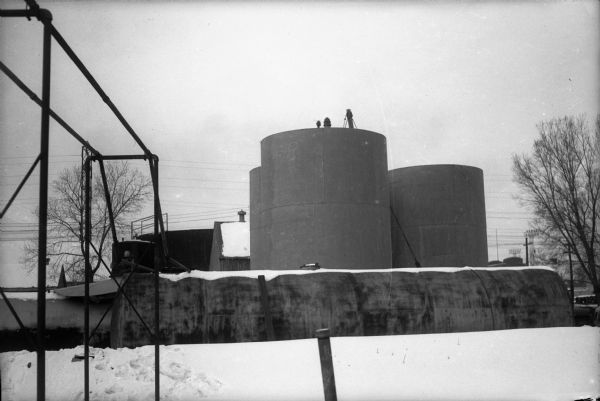Man standing on bulk tanks at Cities Service Oil Company Plant, 815 East Main Street, where an explosion killed welder Harold Michelson.