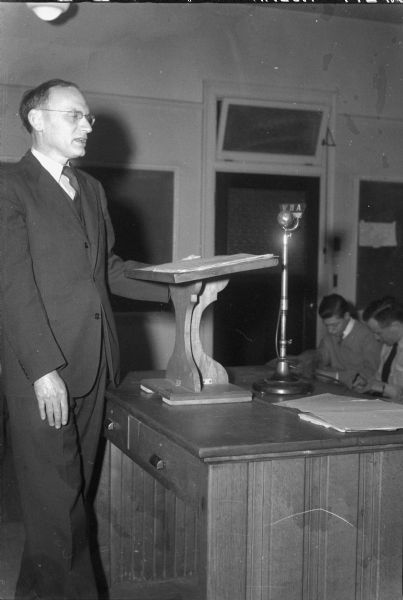 Professor Merle Curti at WHA Microphone Prof. Merle Curti at a podium broadcasting a lecture to his class over WHA on "Social and Intellectual History of the U.S."
