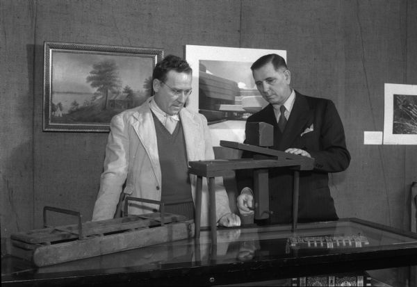 Professor J.F. Kienitz, on the left, and Edward J. Law, committee member of the Historic American Buildings Survey in Wisconsin, examining a miniature model of an early "shaving horse" used for making shingles. The "shaving horse" is part of an exhibit of the Wisconsin Historical Society on Wisconsin's early architecture.