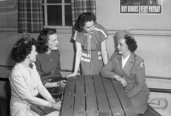 Group portrait of three members of "Parlor Tricks" being instructed by Mrs. Frances Maloney, Red Cross recreation director. Pictured left to right: Lorraine Jones, 130 East Gorham Street; Helen Lunde, 2140 University Avenue; Mary MacLennan, 711 East Johnson Street; and Mrs. Maloney. The "Parlor Tricks" are a group of young women volunteers who entertain convalescent patients at the Army Air Force regional hosptial at Truax Field.