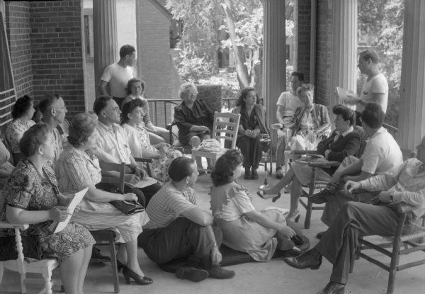 Group of men and women listening to a speaker at the Abraham Lincoln School, Summer Institute. The Abraham Lincoln School for Social Science of Chicago, Illinois, sponsored a Summer Institute in Madison for several summers, including 1945.  The students who attended the two week sessions were mostly adult union workers and their families.  They lived in rooming houses on Langdon Street and Lake Lawn Place, attended lectures and participated in recreational activities. The photographs show the teachers with groups of students, both indoors and out-of-doors, the students participating in recreational activities such as boating and badminton, and the children with a day care worker.<br>The School was run by former University of Wisconsin Associate Professor of Classics Alban D. Winspear. Their textbook was called "Why Work for Nothing," espousing Marx's theory of value.  The school had a communist / leftist philosophy and was often confused with the University of Wisconsin's School for Workers.</br>