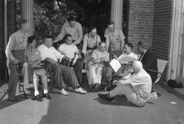 Group of students listening to a lecture on a porch. The Abraham Lincoln School for Social Science of Chicago, Illinois, sponsored a Summer Institute in Madison for several summers, including 1945. The students who attended the two week sessions were mostly adult union workers and their families. They lived in rooming houses on Langdon Street and Lake Lawn Place, attended lectures and participated in recreational activities. The photographs show the teachers with groups of students, both indoors and out-of-doors, the students participating in recreational activities such as boating and badminton and the children with a day care worker. The School was run by former University of Wisconsin Associate Professor of Classics Alban D. Winspear. Their textbook was called "Why Work for Nothing" espousing Marx's theory of value. The school had a communist / leftist philosophy and was often confused with the University of Wisconsin's School for Workers.
