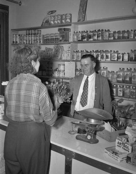 Jack Pelton, operator of the Pelton Seed and Supply Company, 1004 South Park Street, shown with a customer in his store.