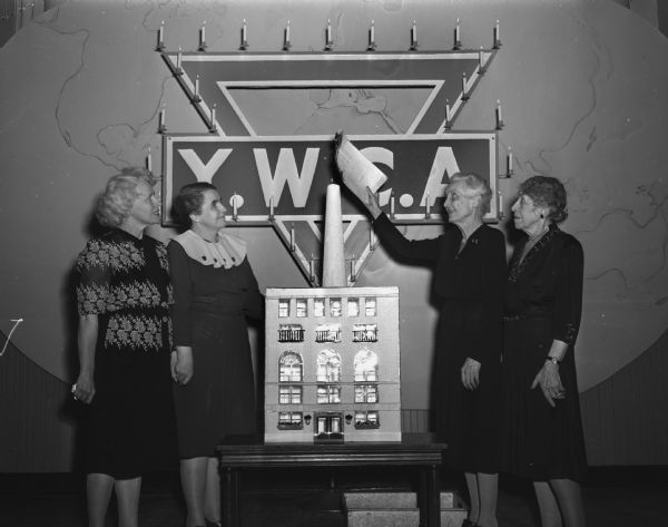 Shown taking part in the "burning of the mortgage" ceremony Thursday night at the Madison YWCA are (from left to right): Mrs. C.V. La Duke, who formerly was a member of the YWCA staff and who represented Miss Jane Sherrill, an early secretary of the association who was unable to participate in the ceremony; Mrs. Loran B. Cockrell, president of the current board of directors; Mrs. H.S. Richards, a past president of the board; and Mrs. John A. Aylward, who was president at the time the building was completed in 1919.  Also shown is a model of the building.