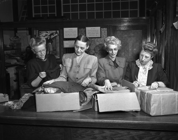 As part of their observance of Zonta Week, members of the Madison Zonta club are shown packing boxes of clothing to be sent to Zontians in Denmark, Holland, Finland, Germany, and Austria for distribution in their countries. From left to right, Mrs. O.A. (Lillian) Fried, Shorewood Hills; Mrs. Marius (Erdis) Hansen, 118 Breese Terrace; Miss Sadie C. Munson, 317 Elmside Boulevard, and Mrs. Leo R. (Helen) Mullarkey, 17 South Hancock Street.