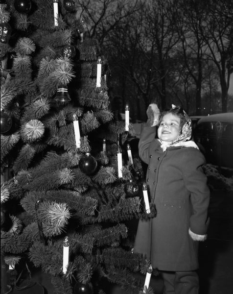 Natalie Schwartz, 137 Talmadge Street, admiring a Christmas tree outdoors.