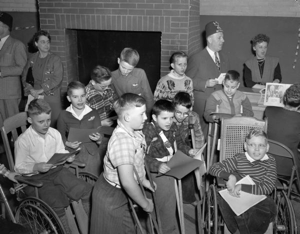 Floyd Ferrill leads a group of handicapped children in a Christmas carol at the Madison Shriners yule party at the Washington Orthopedic School, 545 West Dayton Street.