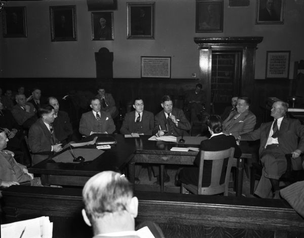 Hearing at the Dane County Court House attended by city officials and fuel dealers concerning temporary fuel oil shortages. Pictured clockwise around the table are: A.S. Hitch and Leo Wohlferd, Standard Oil Company, Madison; A.J. Fiore, Fiore Coal and Oil Company, Madison; Building Commissioner Ray Burt and City Manager Leonard Howell, Madison; H.W. Miller and F.R. Lucas, Wadhams Division, Socony-Vacuum, Madison; County Board Chairman Paul A. Robinson, Sun Prairie, county fuel coordinator, and Deputy County Clerk Clara Reick, secretary of the meeting.