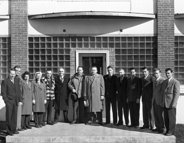 Group portrait of fourteen employees standing at the front door of the Regal Products, Ltd. at Gays Mills. E. Tex Reddick is the company president.