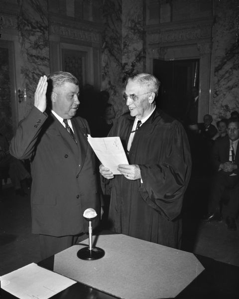 John E. Martin, left, is shown as he took the oath of office as a member of the Wisconsin Supreme Court. Chief Justice Marvin B. Rosenberry is administering the oath to the former attorney general who was appointed to the high court by Governor Oscar Rennebohm.