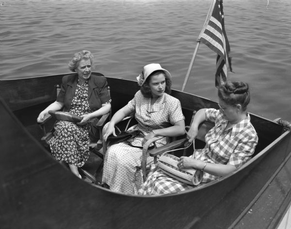 Mrs. D.A. Forsberg and Guests Pictured in the Forsberg's inboard motorboat docked at the Edgewater Hotel pier are Mrs. D.A. (Claudia) Forsberg, at right, and at left, her guests Mrs. Edward Mulholland and Mrs. Maynard Fessenden, both of Chicago. The guests accompanied their husbands to a meeting of the executives of the National Folding Paper Box Association held in Madison.