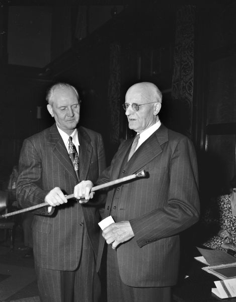 John Berge, left, secretary of the Wisconsin alumni association, presents the gold headed cane to E.E. Brossard, right, age 85, Class 1888, state reviser of Statutes. He was the senior member present at the University of Wisconsin Half Century Club for alumni who graduated 50 or more years ago. The presentation was held at their annual meeting.