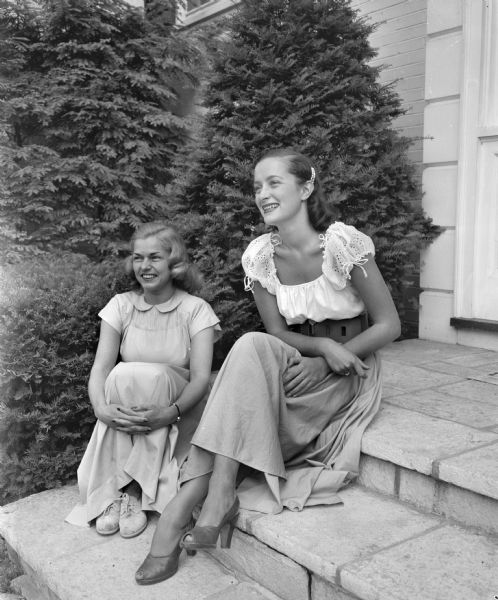 Co-chairmen of "The Assembly" dance committee are Harriet Sisk, on the left, and Marjorie Bolz on the right, posing outdoors on steps.
