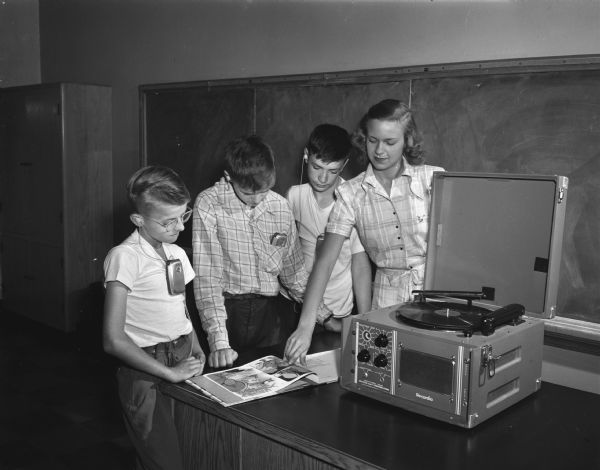 Participants in a large-scale hearing clinic held at Washington School in Madison and sponsored by the University of Wisconsin departments of speech and education with the cooperation of the state bureau for handicapped children. Marion Olejniczak, Milwaukee, is shown playing a phonograph record with related pictures in books with three children.