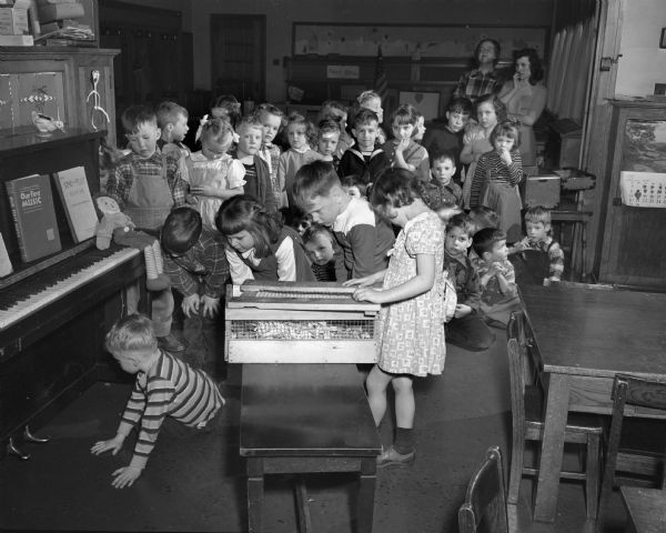 Dudgeon School Students Johnny Rengstorff looks for a missing hamster near a piano, while Danny Steihl, Susan Lorenz and Phillip Johnson watch. Judy Erb examines the hamster's cage and the other Dudgeon School five-year-olds look on.