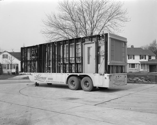 Truck carrying Lustron house sections  to be assembled on a building site.