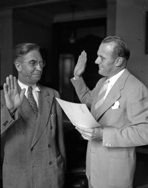 George E. Watson, Wauwatosa, at left, being sworn in as the new State Superintendent of Public Instruction, by Robert C. Zimmerman, Assistant Secretary of State, at right.