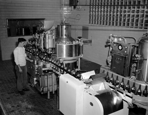 Canada Dry Bottling Company Plant Slightly elevated view of the interior of the Canada Dry Bottling Company plant at 3313 University Avenue, showing the bottling line. One person is standing near the machinery.
