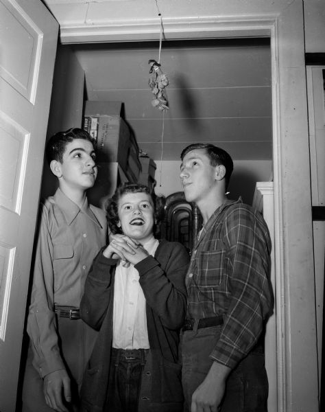 Shown contemplating what may be the results of her standing under the traditional mistletoe is Connie Connor. On her left is Arlen Rosenbloom and on her right, Lester Levine.