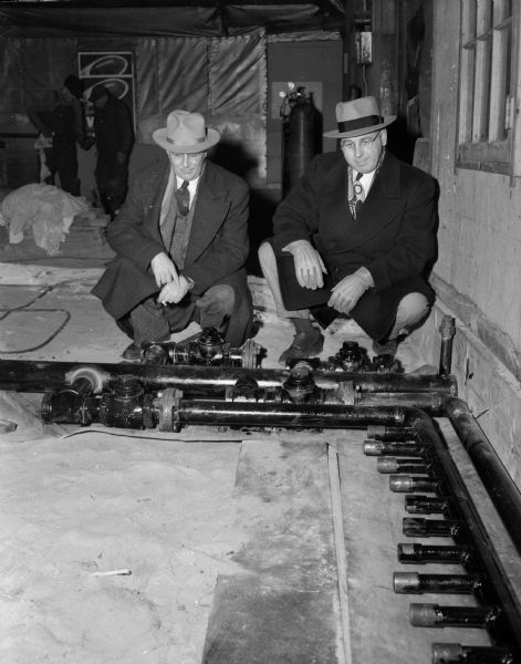 Two members of the Madison Curling Club inspecting the pipes that will furnish artificial ice at their new clubhouse at Burr Jones Field on West Washington Avenue.