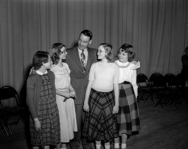 Roger E. Trafford, principal at West junior high school, standing in an auditorium with his students who won the first four places in the school spelling bee. His students, left to right, are: Gretchen Idhe, fourth place; Diana DeLess, third place; Virginia Wallace, runner-up; and champion Carol Jane Beery.