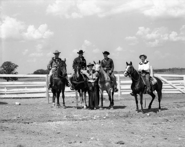 Five members of the Madison Junior Chamber of Commerce dressed in western costume prepare for a rodeo at the Dane County fairgrounds. Four of the members re sitting on horseback. The JCC was denied a permit for use of the fairgrounds because of a schedule conflict.
