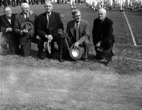 Wisconsin vs. Marquette Football Game Five members of the University of Wisconsin 1900 football team who were honored during the pregame ceremonies of the Wisconsin vs. Marquette game kneel along the sideline. From left are: Paul Trait, Ft. Atkinson; A.F. Larson, Sioux Falls, South Dakota; A.A. Chamberlain, Huron, South Dakota; Ed Cochems, Madison; and Paul Murphy, Rockford, Illinois.