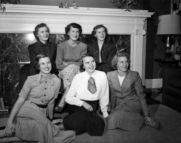 Sorority Pledges Madison pledges of the Alpha Phi sorority pose for a group portrait while seated in front of a fireplace. In the front row are Susan Batiste, Joan Fagan, and Alicemay Gerretson. In the second row are Mimi Mackin, Ann Hastings, and Bunny Mackin. The Mackin girls are twins and the family recently moved to Green Bay.