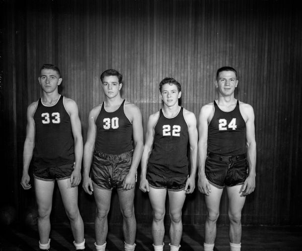 Members of the East High School basketball team posing for a group portrait in uniform. Left to right: Gordy Morris, Gary Messner, Ted Blackney, and Lloyd Sarbacker.