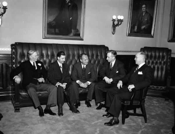 Walter J. Kohler, Jr. is sitting on an oversized sofa in the Governor's office prior to his inauguration ceremony. With him are Wisconsin's other constitutional officers. Shown left to right: Secretary of State Fred R. Zimmerman, Lieutenant Governor Geroge M. Smith, (Kohler), Attorney General Vernon W. Thomson and Treasurer Warren R. Smith.