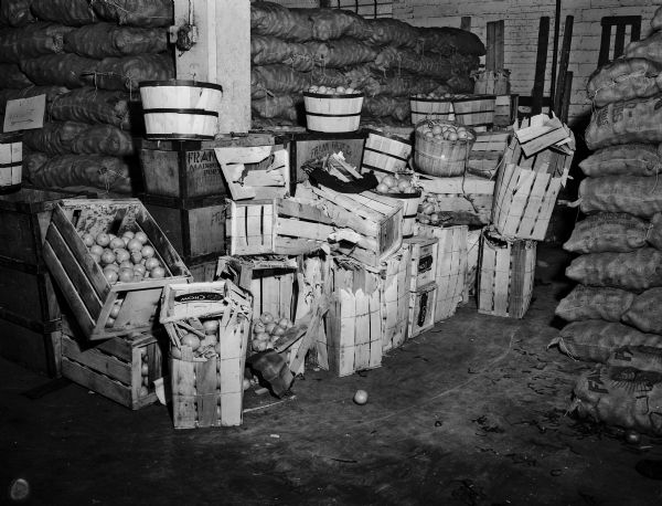 Crates of oranges, some damaged, are stacked in a storage area after being unloaded from an Illinois Central Railroad car.
