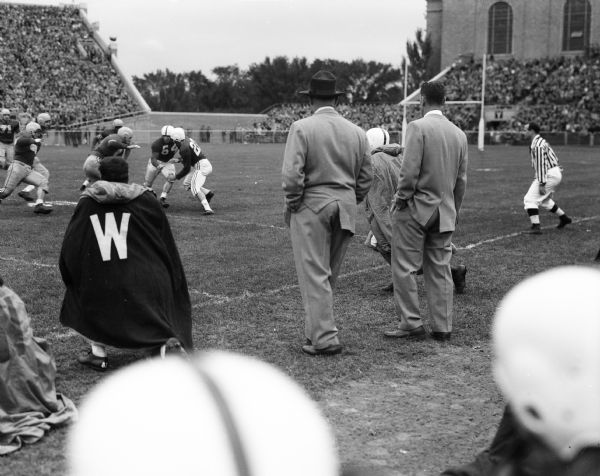 Two coaches watch a play from the sidelines of the University of Wisconsin vs. Marquette football game at Camp Randall stadium.