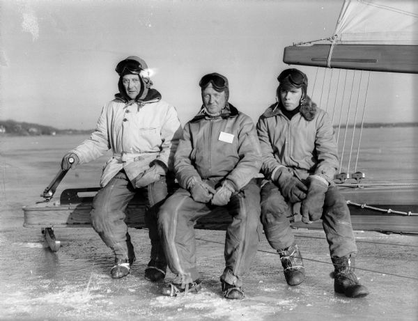 The Madison crew sits on their iceboat, the "Mary B," that raced in the Northwestern Ice Yachting Association ice regatta on Lake Monona. From left to right are: Skipper Carl Bernard, Norm Braith, and C.J. Johnson.