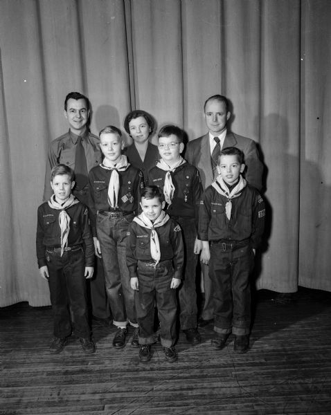 Group portrait of five Cub Scouts as they receive awards at Emerson School. At front is David Todd. First row, left to right: James Wahlber, Jerry Lomas, David Gilpin, and Philip Lindemann. Back row:  Joseph Cox, cubmaster; Evelyn Gilpin, PTA president; and Emery Bainbridge, Emerson principal.