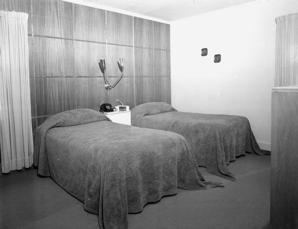 Residence of Tom and Ruth McGovern Interior view of the master bedroom in the home of builder Tom McGovern and his family at 25 Hiawatha Circle. Mahogany walls form a backdrop for the twin beds and nightstand of the room that features a color scheme of shades of green and brown.