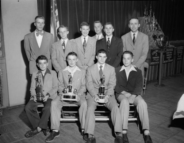 Group portrait of members of the Blessed Sacrament Parochial school athletic teams, their coaches and sponsors who were honored at the school's annual banquet. Front row left to right: Jack Valentine, David Hackworthy, Mike Donagan, and Dan Lamphear. Back row: Lou Genter, Knights of Columbus; Buck Asper; Pat Heffernan; Ed Miller, football and baseball coach; Earl (Shorty) Ross, basketball coach; and Don Purcell, Catholic War Vets.