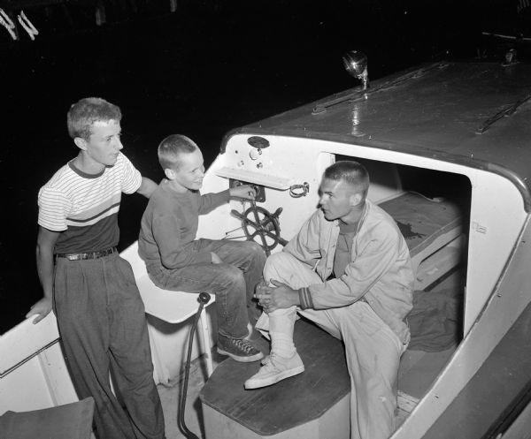 Phil Sawin, Frederich Rikkers, and Jim Schneiders, left to right, relaxing in a power boat during the Mendota Yacht Club moonlight regatta and picnic supper.