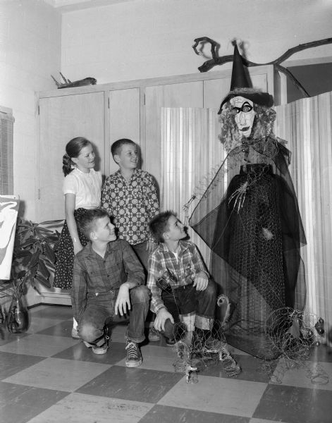 Sixth grade students at Midvale School constructed a witch out of chicken wire for the Halloween exhibit in the art gallery at school. The children left to right kneeling are Tom Rygh, Don Tranchita, and standing are Karen Michelson and Wayne Attoe.