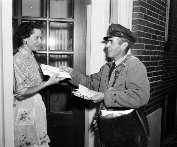 Mail carrier Joseph L. Ripp delivers Christmas seals to Mrs. M. Leslie (Gretchen) Holt at 133 Langdon Street. They are for the traditional fund raising drive of the Madison Tuberculosis Association.